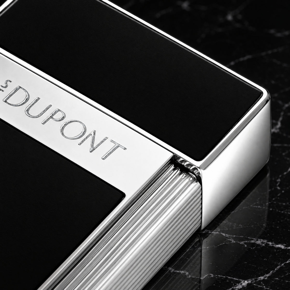 Close-up of the S.T. Dupont Biggy lighter in black lacquer, showing the engraved S.T. Dupont band and fluted chrome roller
