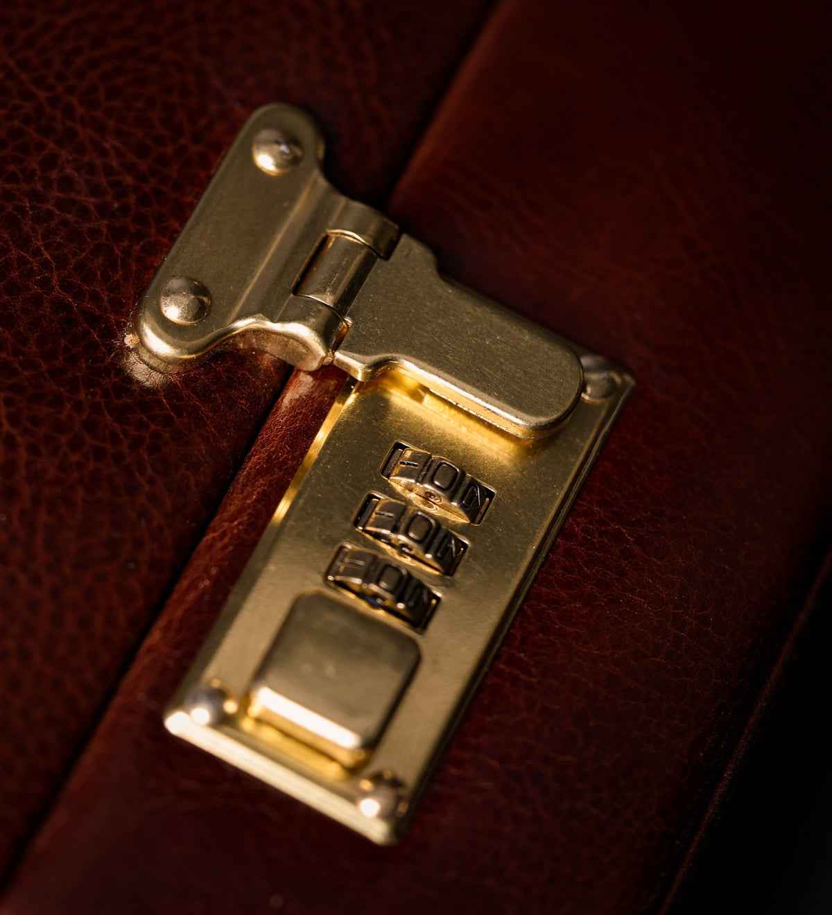 Brass combination lock and clasp on the Vendetta brown leather attaché case, close-up