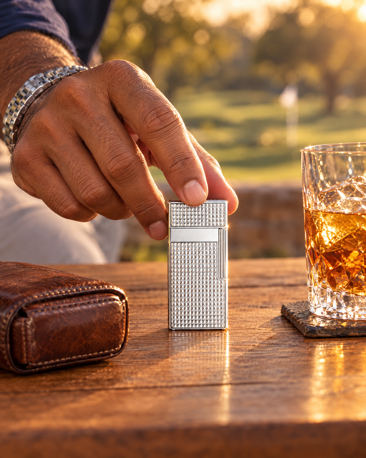S.T. Dupont Biggy Lighter — Diamond Head, Chrome, lifted from a teak table beside a leather cigar case in late sun