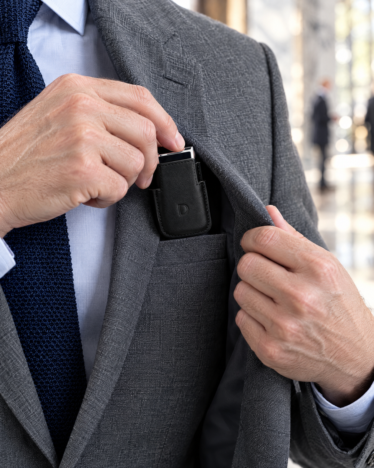 S.T. Dupont Ligne 2 Lighter Case — Black Leather, slipped into the inside breast pocket of a grey suit jacket