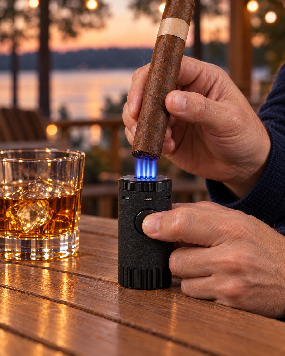 Xikar Volta quad-jet tabletop lighter on a porch table, four blue jets toasting the foot of a cigar held above it