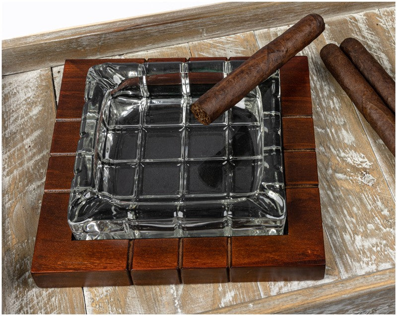Wood and crystal cross-hatched ashtray with a cigar, on a wood surface