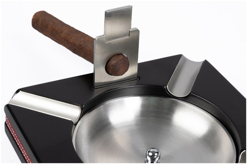 Leather-trim cigar ashtray with the built-in cutter in use on a cigar