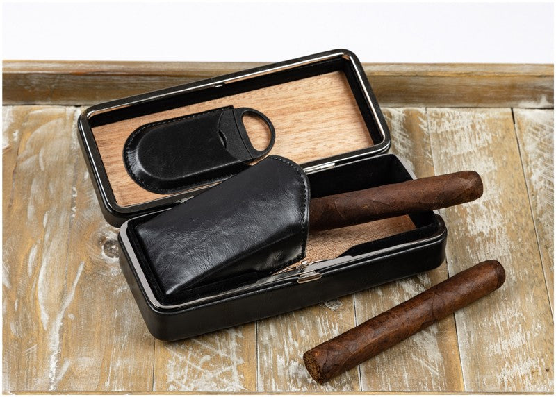 Three-cigar snap-lock case open on a wood table with cigars and the removable cutter