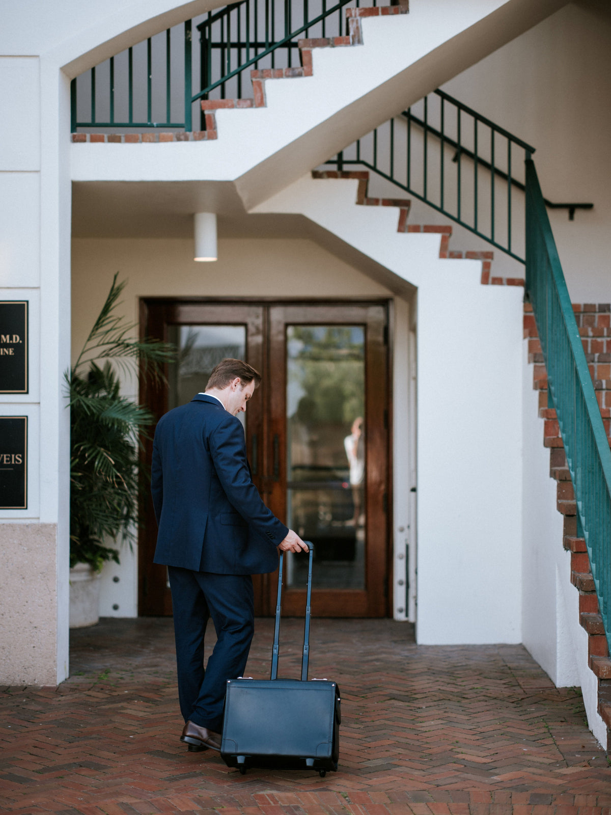 Man in a suit pulling the black Litigator wheeled catalog case through an entrance