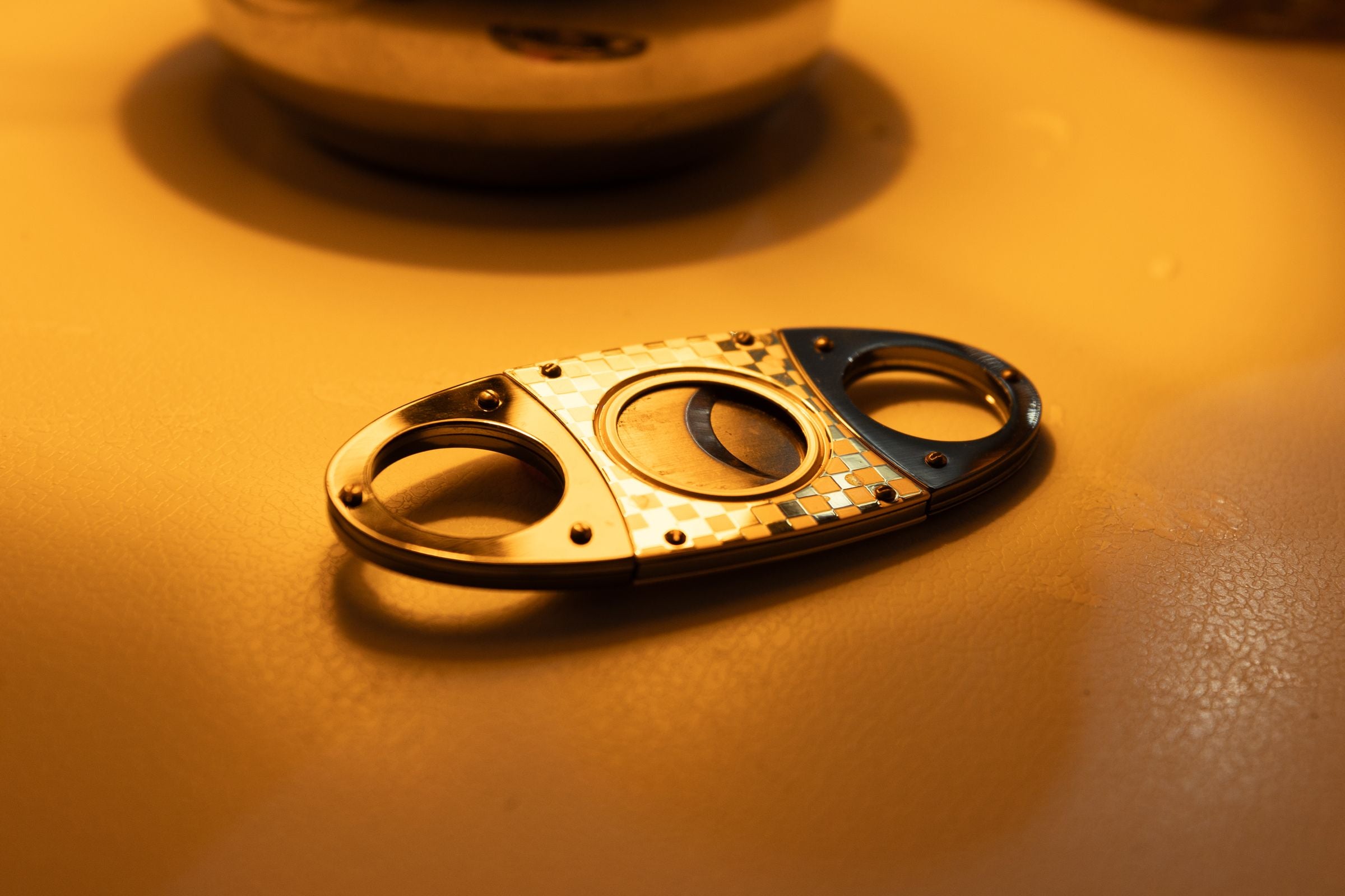 A polished stainless steel cigar cutter, the sole focus of the frame