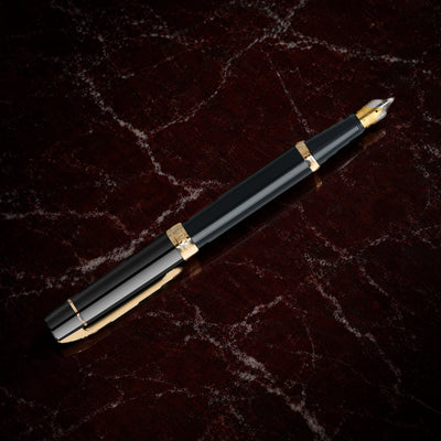 Sheaffer 300 Pen — Glossy Black with Gold Trim: the fountain pen in glossy black lacquer with gold-tone trim, on garnet marble