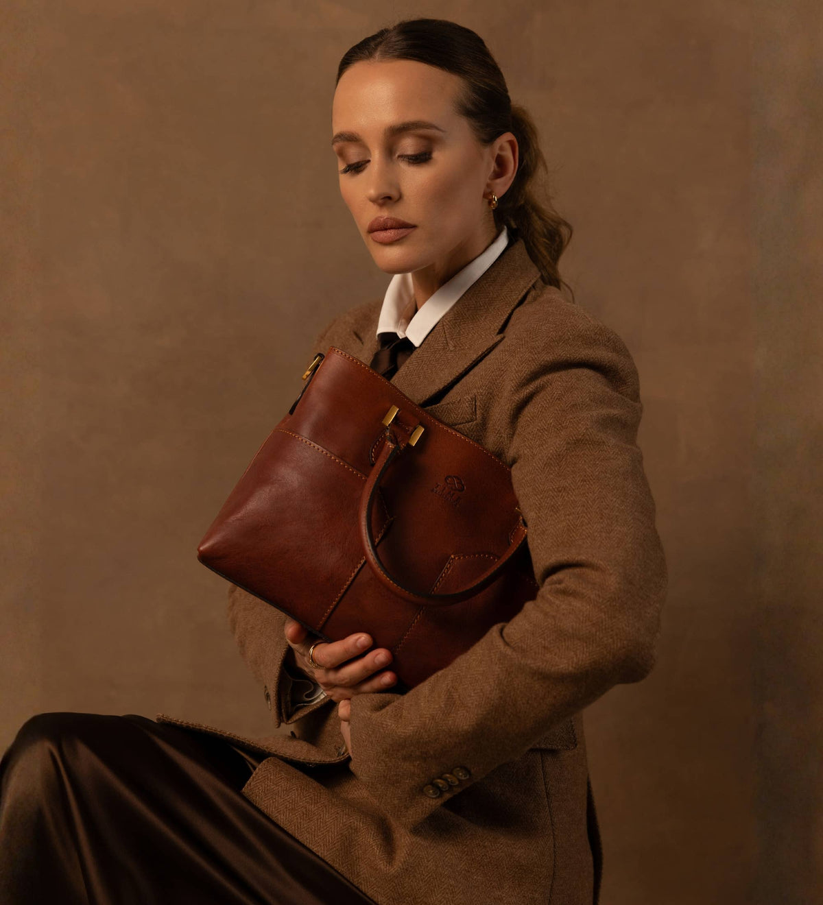 Camilla cognac leather shoulder bag held under the arm by a model