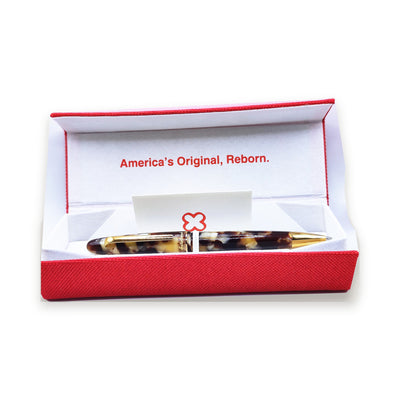 The Esterbrook Estie ballpoint in Tortoise resting in its red Esterbrook presentation box, lid open, with the maker's card
