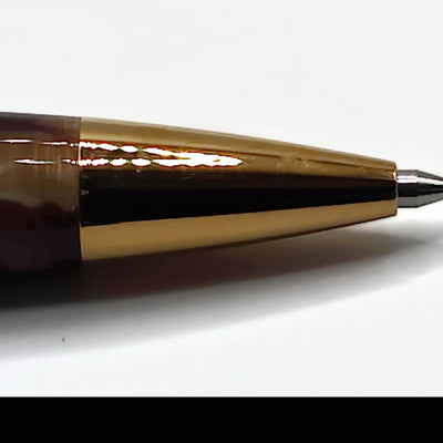 Macro view of the Esterbrook Estie ballpoint tip in Tortoise and gold, the polished gold cone and steel ball point shown close up on white paper
