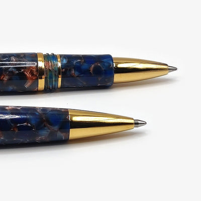 The writing ends of the Esterbrook Estie rollerball and ballpoint in Nouveau Bleu compared close up: the rollerball above with its ringed grip section and short gold cone, the ballpoint below running smooth to a longer gold taper