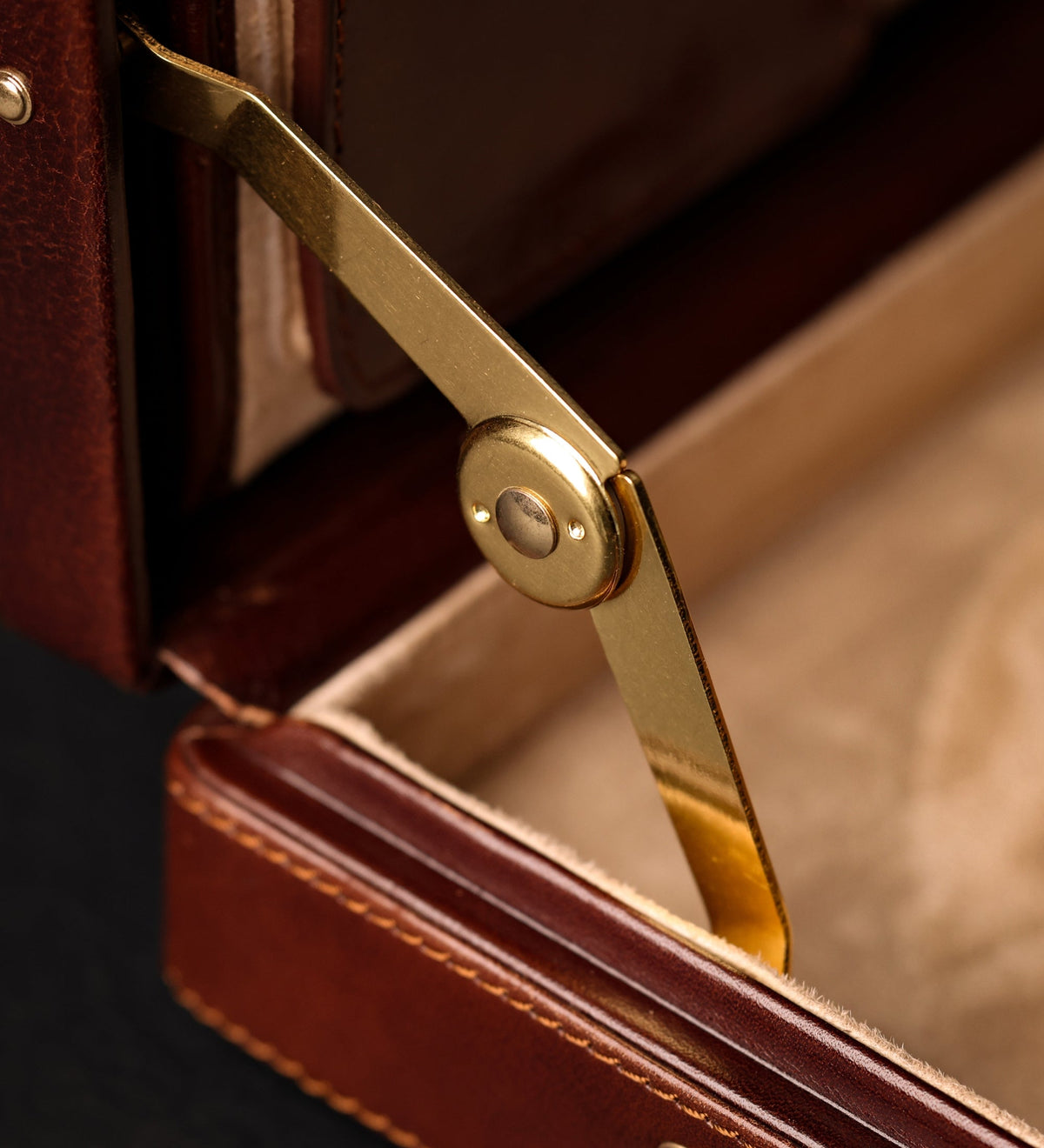 Brass hinge arm inside the open Vendetta brown leather attaché case, close-up
