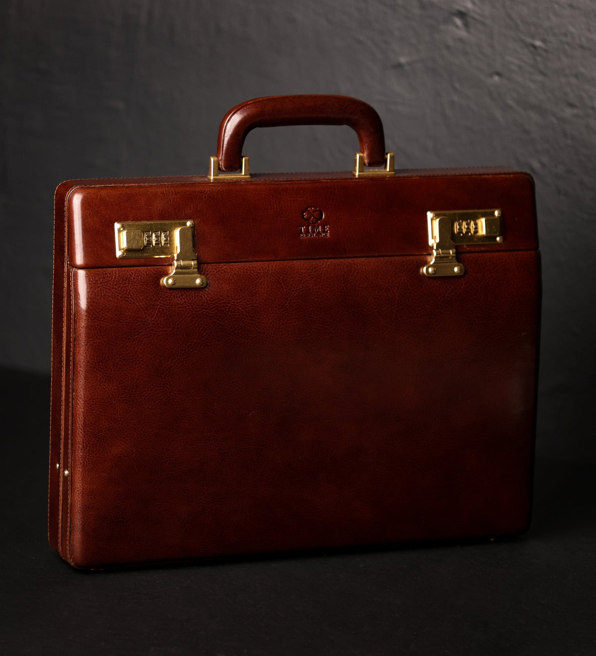 Vendetta brown leather attaché case in Italian Vachetta, three-quarter view on a dark background