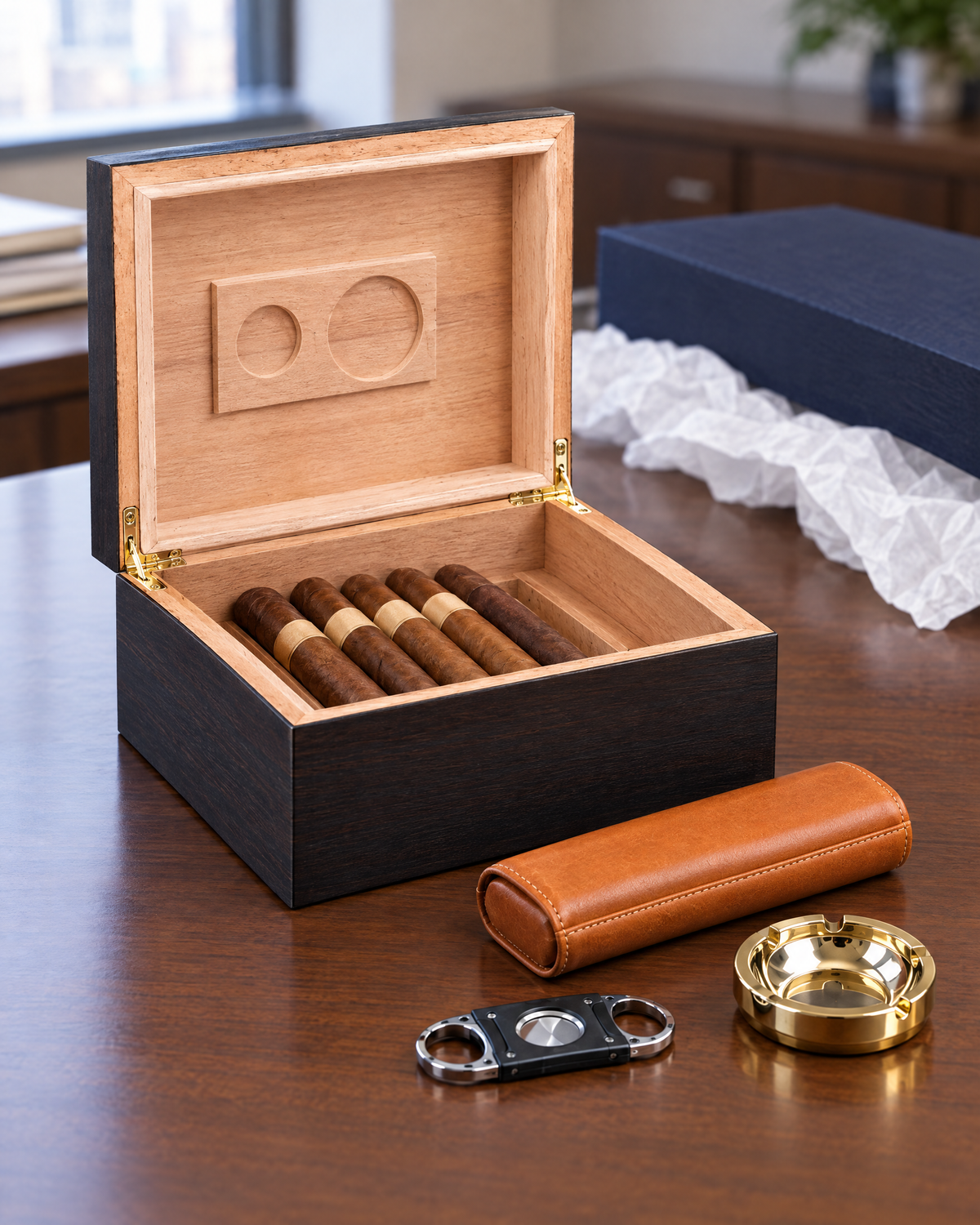 The Diplomat humidor gift set laid out on a desk: humidor open, tan leather cigar case, cutter and small ashtray