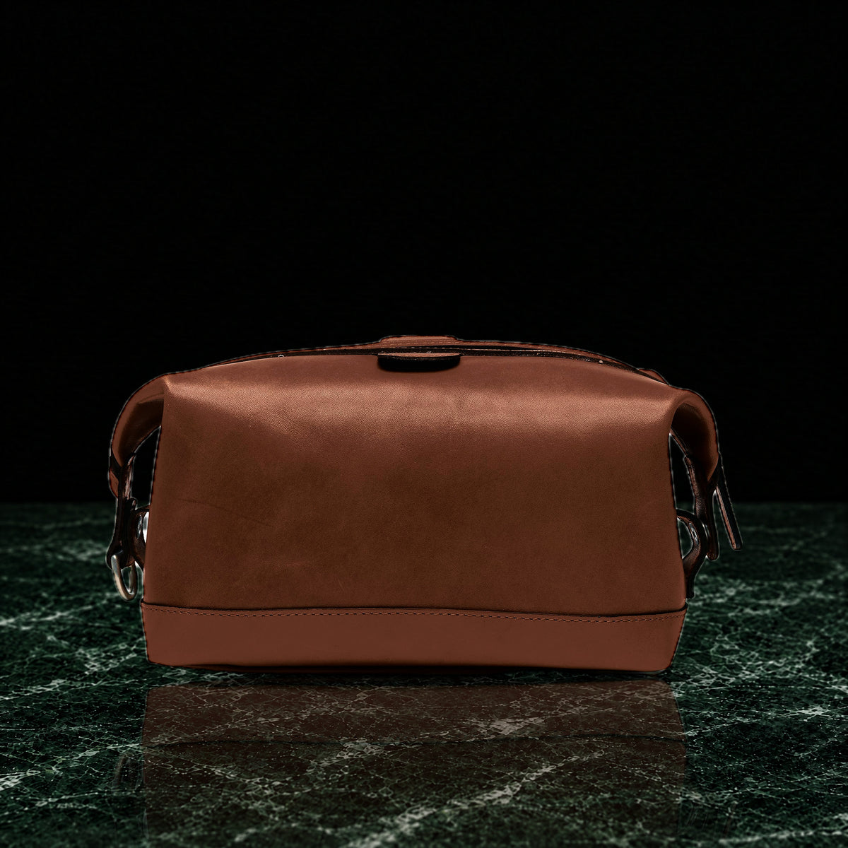 Ryder full-grain leather dopp kit in brown, back view on dark green marble
