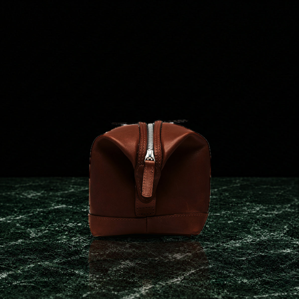 Ryder full-grain leather dopp kit in brown, end view showing the top zip on dark green marble