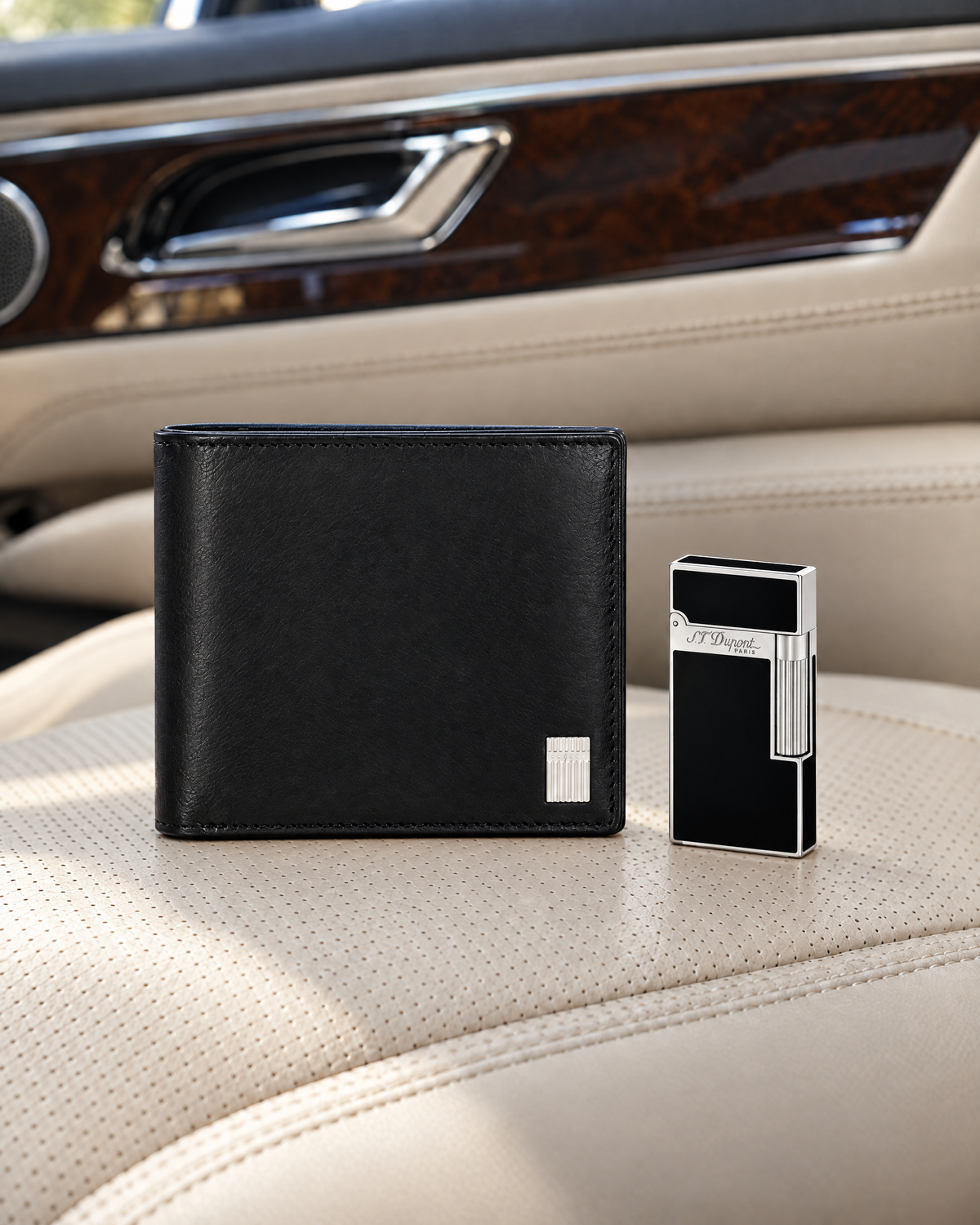 S.T. Dupont Iconic Billfold Wallet in black, closed, resting on a cream leather car seat beside a Ligne 2 lighter in black lacquer and palladium, shown at true relative size