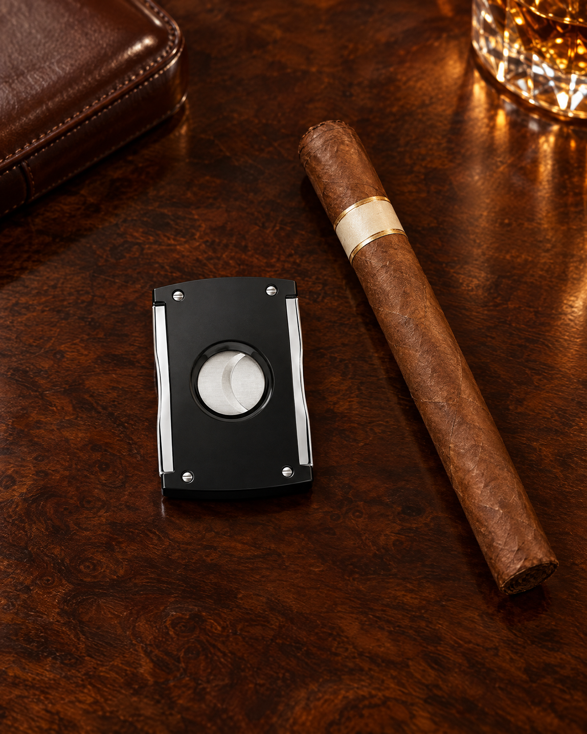S.T. Dupont Maxijet cigar cutter, black and chrome, closed and resting on a polished club table beside an unlit cigar
