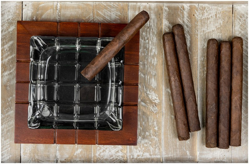 Wood and crystal cross-hatched ashtray with cigars beside it