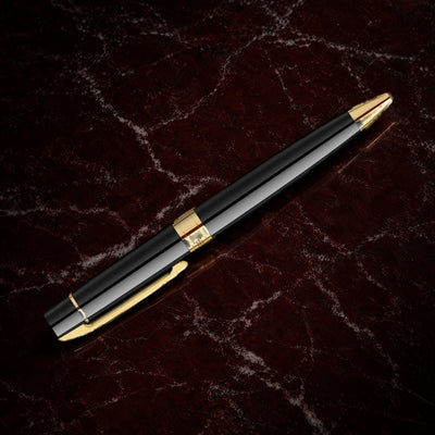 Sheaffer 300 Pen — Glossy Black with Gold Trim: the ballpoint in glossy black lacquer with gold-tone trim, on garnet marble