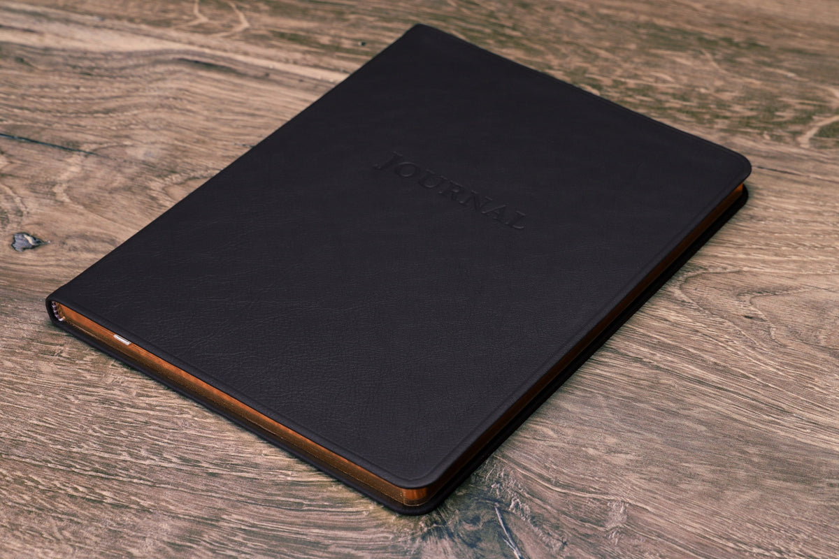 Large Leather Journal in black leather, closed, cover on a wood desk
