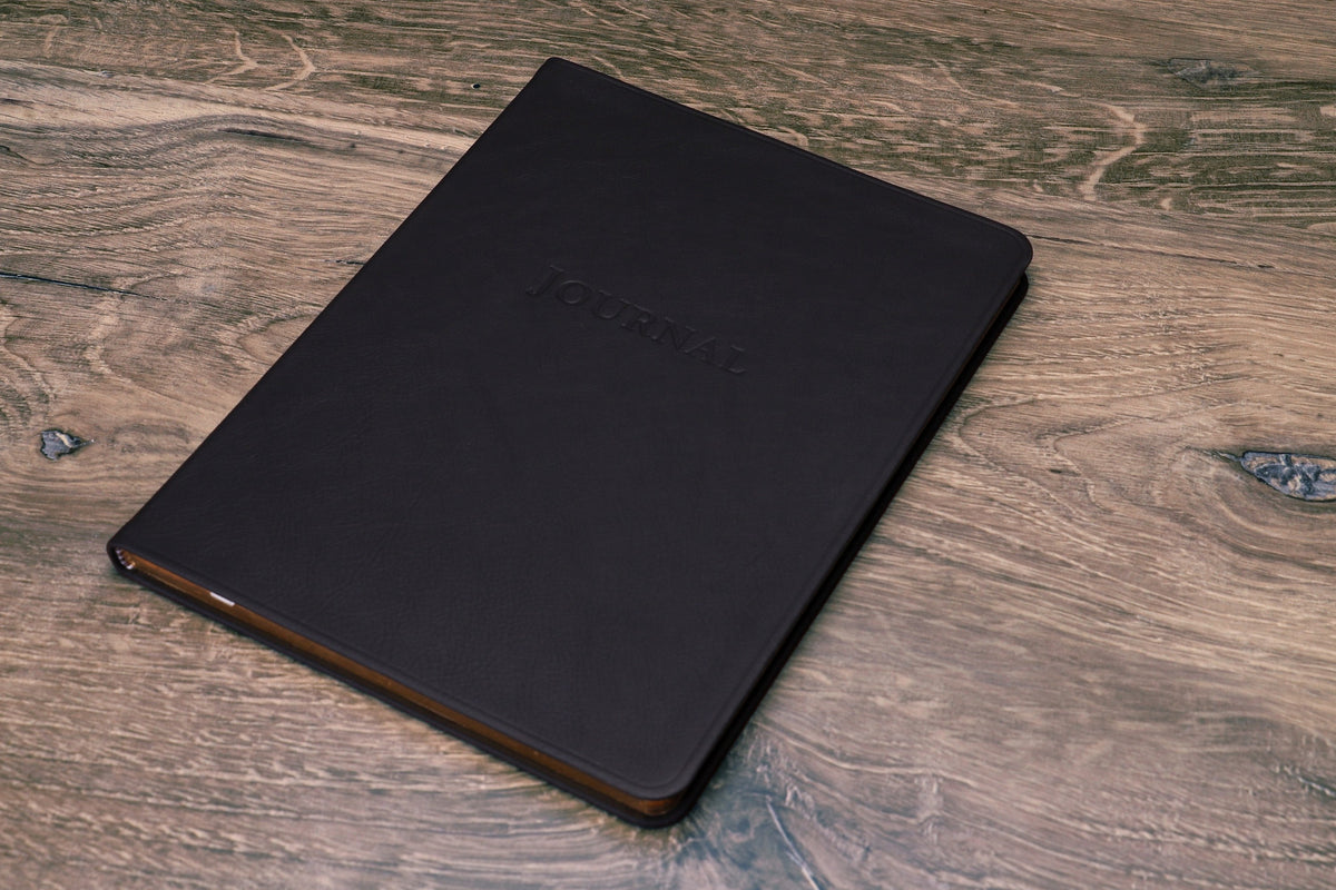 Large Leather Journal in black, closed at an angle showing the spine and gilt page edges