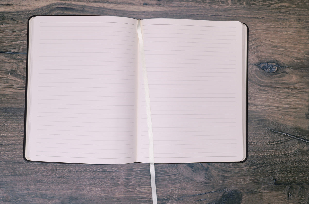Large Leather Journal opened flat to ruled pages on a wood desk
