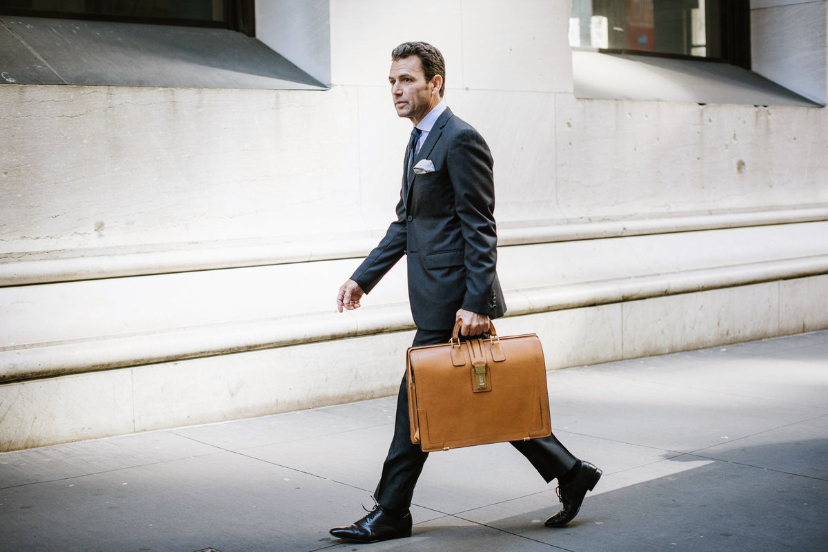 Man in a suit walking with the tan Churchill briefcase past a stone colonnade