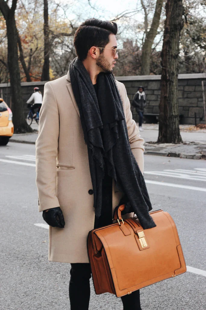 Man in a tan overcoat carrying the Churchill briefcase on a winter street