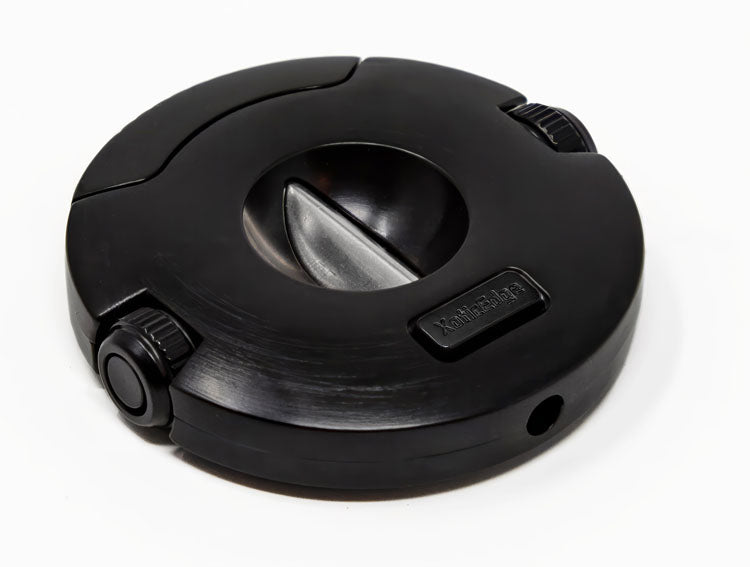 The Xceed cigar cutter from an angle, showing the round black body, the closed V-cut blade, and one screw-off punch